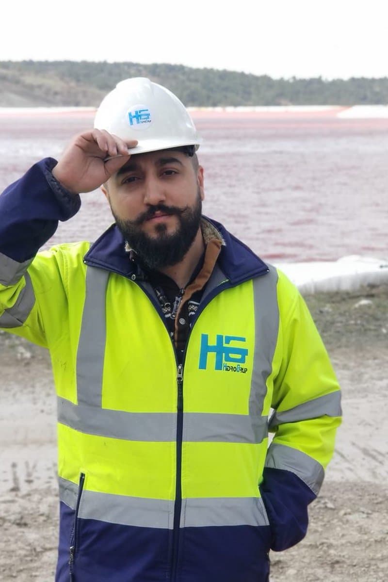 Adjusting a hard hat with a pink pond behind