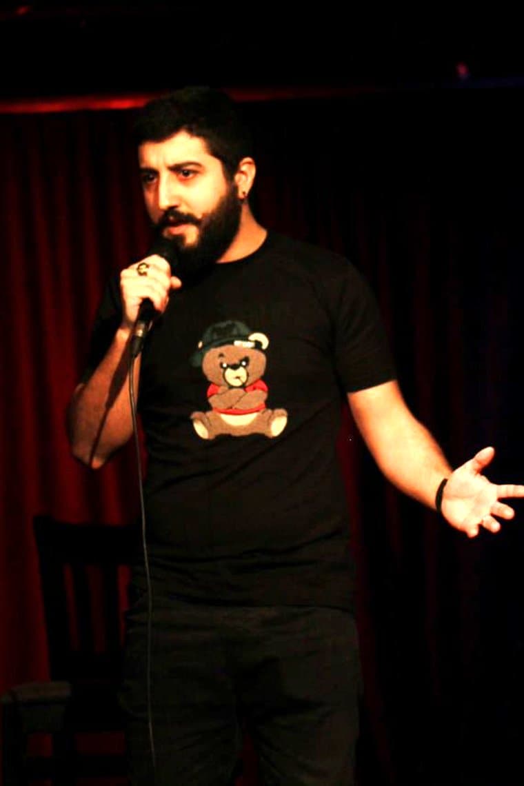 On stage with a microphone, mid-gesture with an open palm
